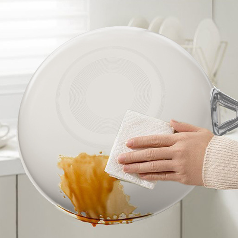 Hånd tørrer sauce af den hvide yderside og bund med et stykke køkkenrulle