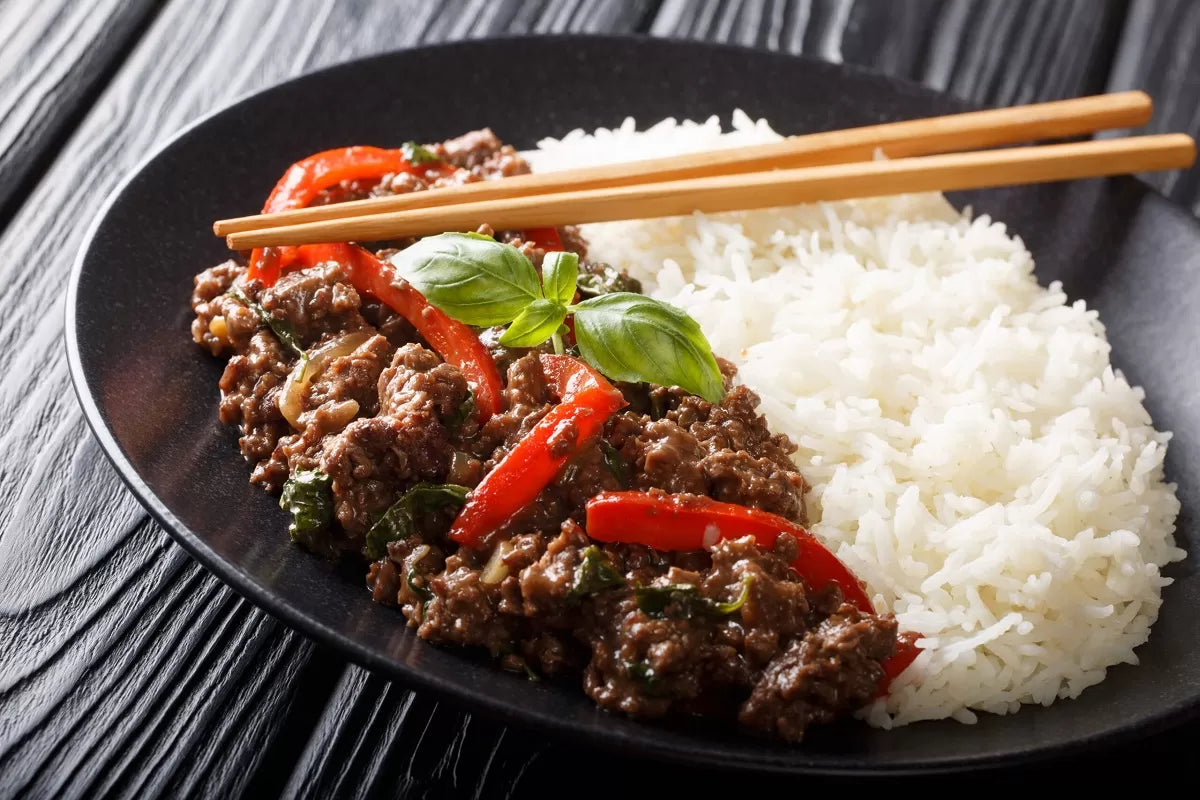Thailandsk wokstegt oksekød med thaibasilikum og jasminris i en wok
