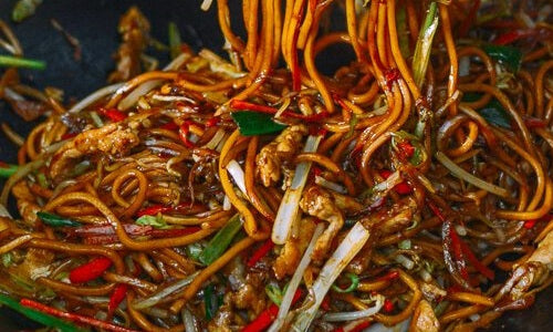 Lo mein med kylling, hvidkål, gulerod og ægnudler i en wok