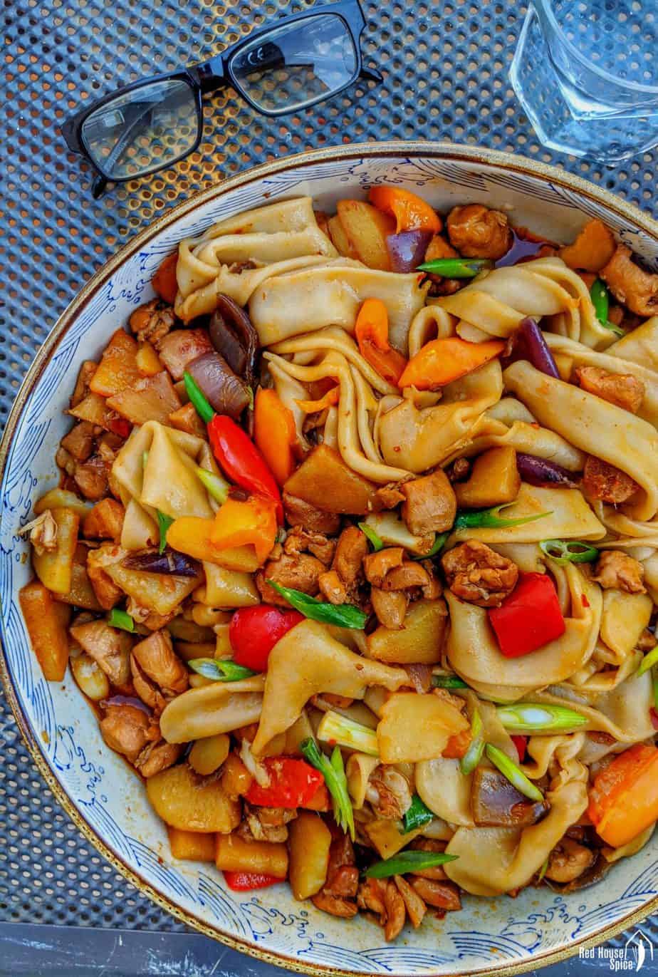 Skål med nudler fra wokken, simret Sichuan-kylling, peberfrugt og forårsløg