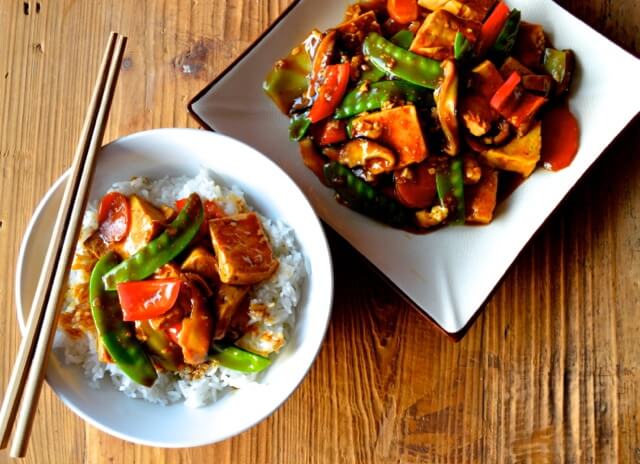 Braiseret tofu med sukkerærter, gulerod og peberfrugt i en wok med blank sauce