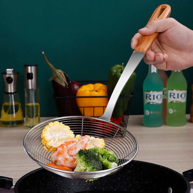 Hånd holder hulsken over en sort pande med majs, rejer og broccoli i kurven