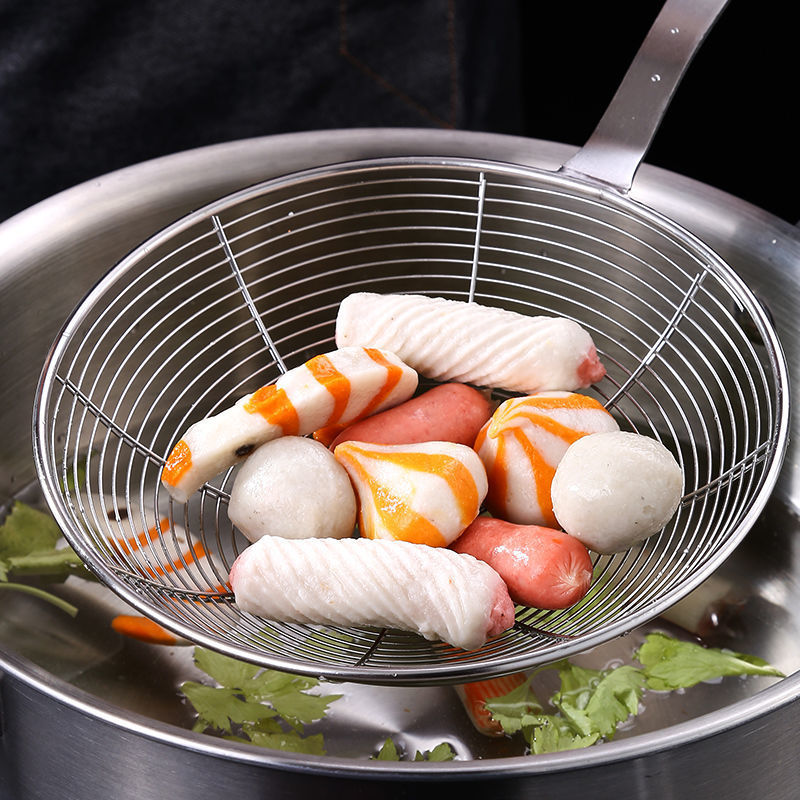 Hulske med fiskeboller og pølser løftet op over en stålgryde med suppe