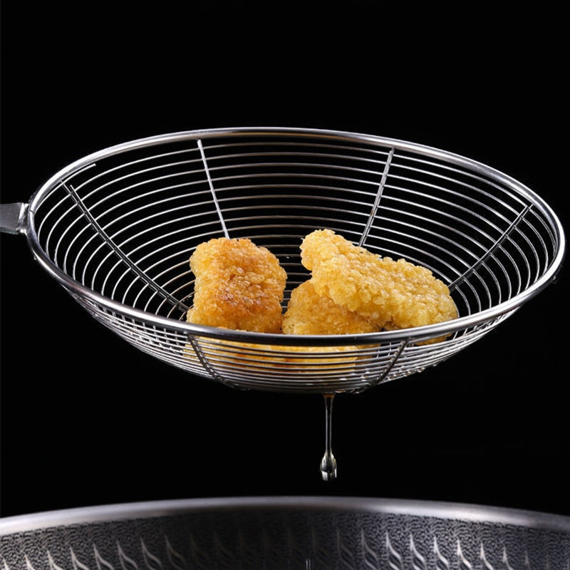 Friterede stykker i trådkurven, mens olien drypper af og tilbage i panden