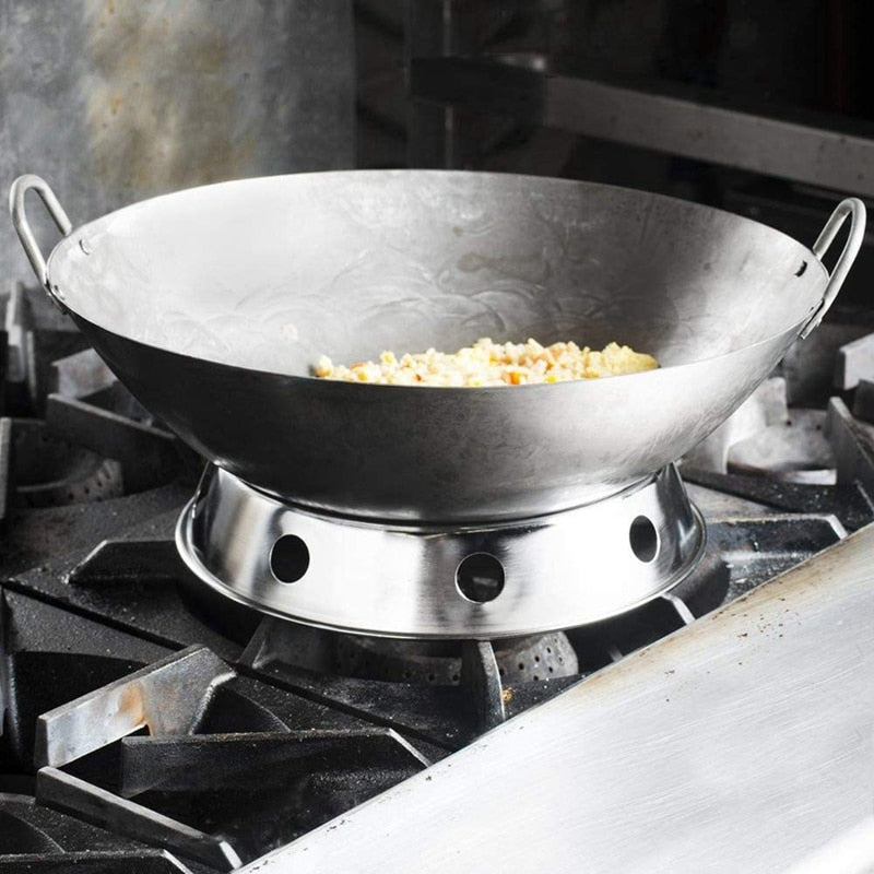 Wok med rund bund og to hanke, der står i en wok holder på et gaskomfur, med ris i bunden