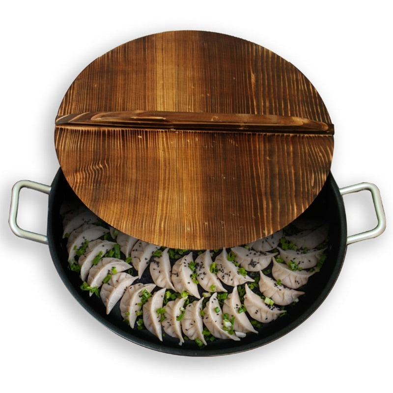 Pande med to hanke og dumplings set ovenfra, med trælåget skubbet halvt ind over