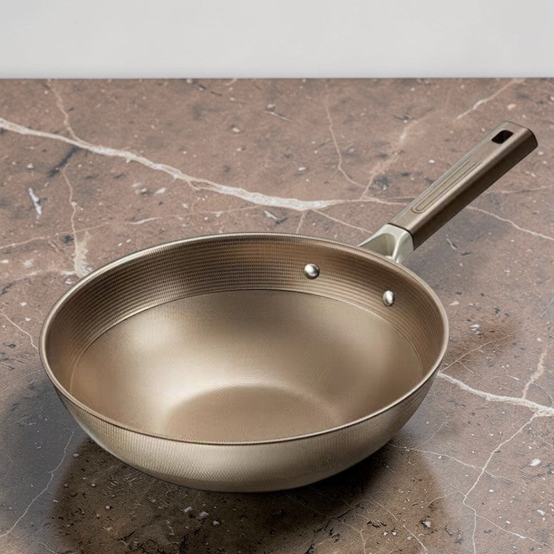Wokken uden låg på en bordplade af brun marmor, set skråt fra siden