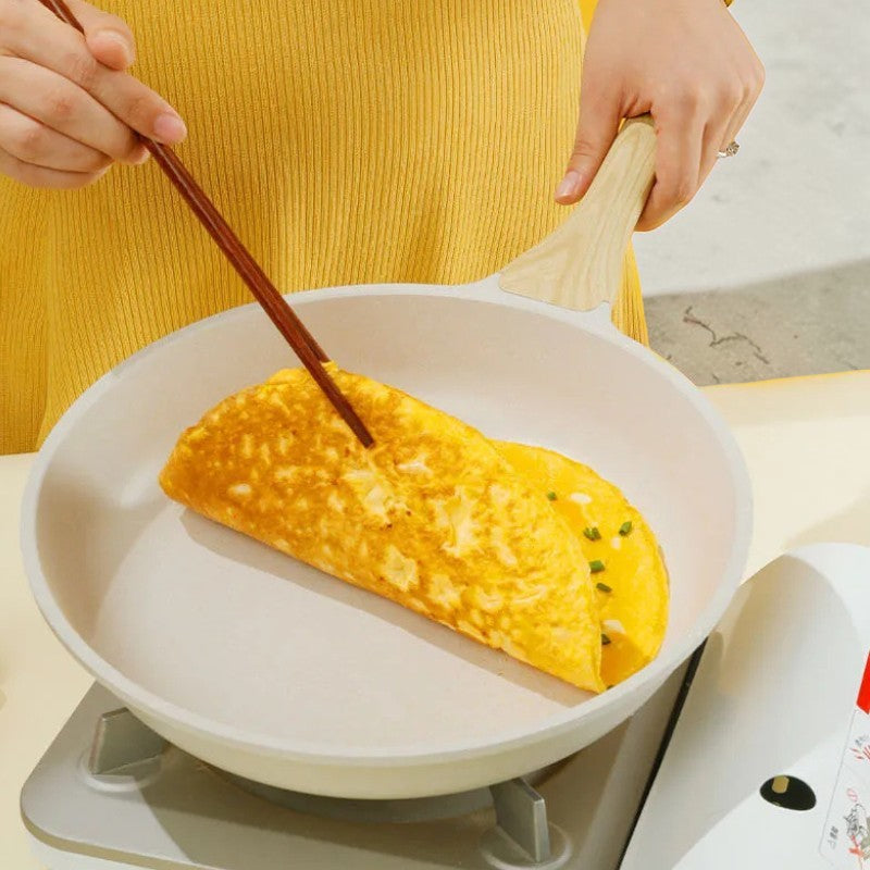 Foldet omelet vendes med spisepinde i panden, der står på et lille gasblus