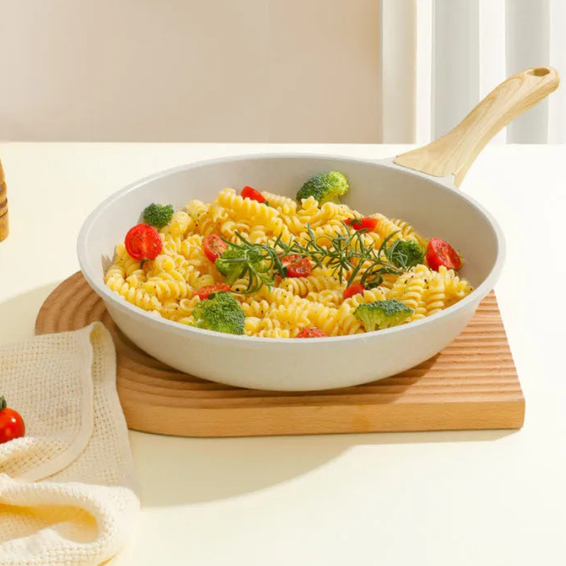 Keramisk pande med pasta, broccoli og cherrytomater på et rillet træbræt