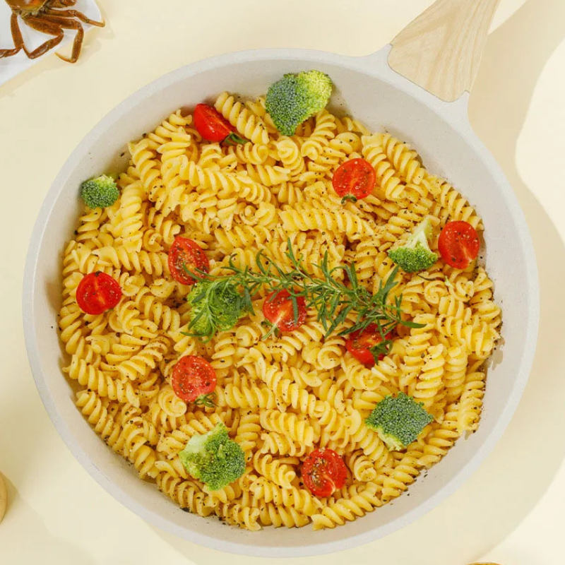 Panden set lige ovenfra, fyldt med pasta, broccoli og en kvist rosmarin