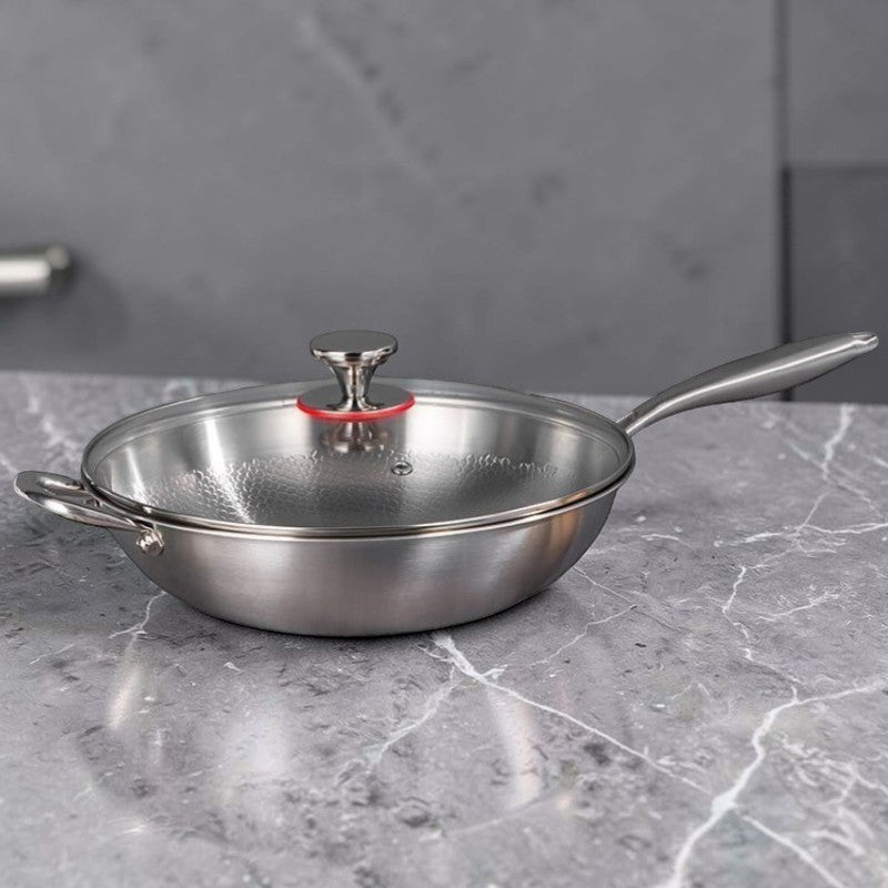 Wok med glaslåg på en grå marmorbordplade foran mørkegrå køkkenskabe