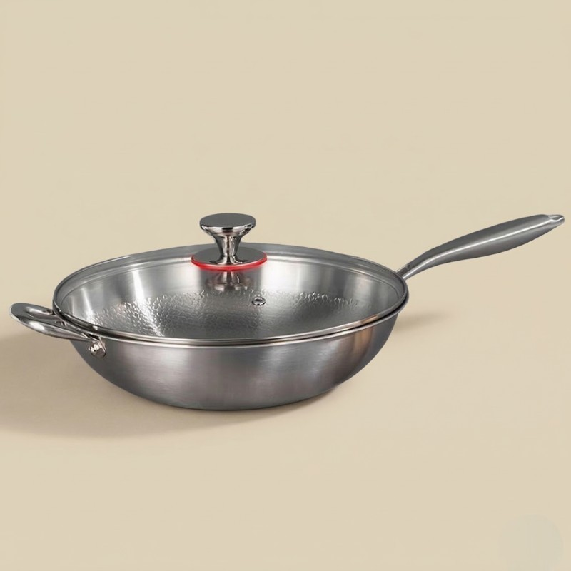 Le Myogi wok i rustfrit stål med glaslåg og stålknop, langt skaft og sidegreb, på en lys beige baggrund