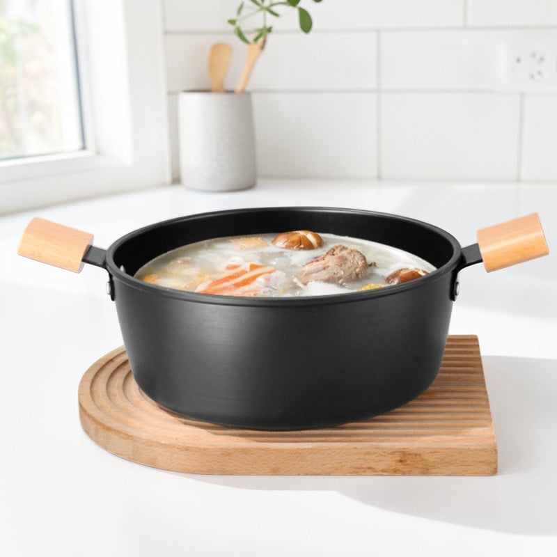 Gryden med suppe, kød og svampe på et bræt af træ i et hvidt køkken