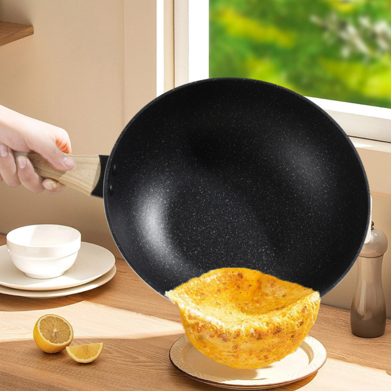 Hånd holder wokpanden med mørk, prikket inderside, mens en gylden omelet glider ud på en tallerken
