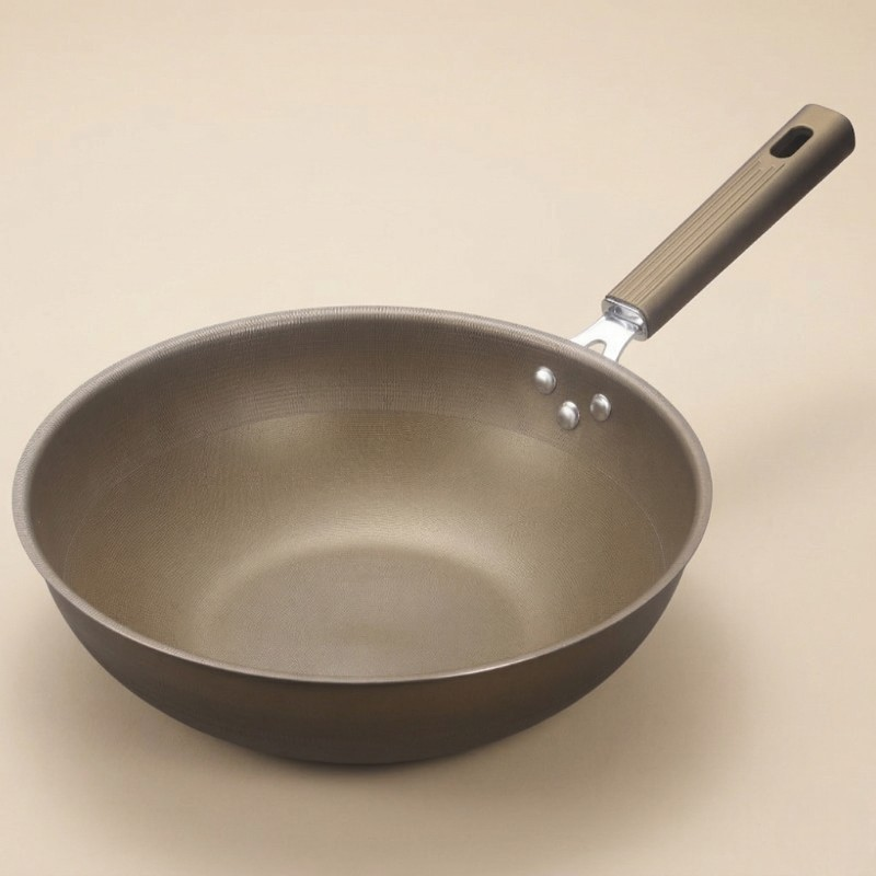 Wokpande uden låg med gyldenbrun overflade og langt skaft på beige baggrund