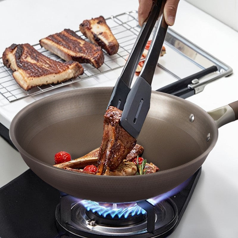 Kød vendes med en tang i wokpanden over gasblusset, mens flere grillede stykker hviler på en rist bagved