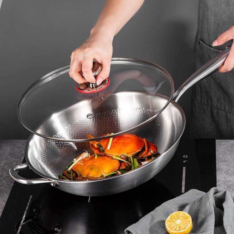 Glaslåget løftes af woken med krabber og forårsløg, mens den står på en induktionskogeplade
