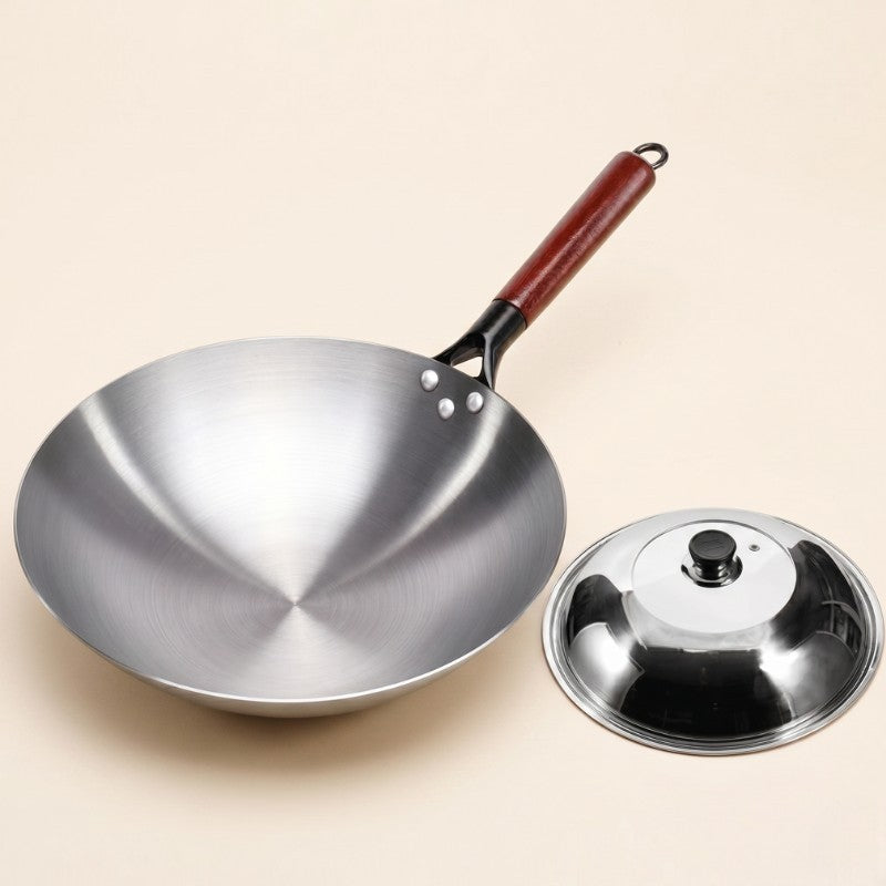 Le Pankon wok i kulstål med træskaft og et blankt låg med knop ved siden af, på lys baggrund