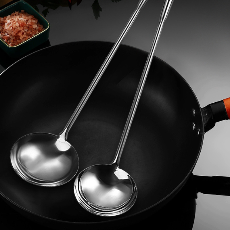 To wokskeer lagt i en tom sort wok med træhåndtag ved siden af en lille skål med lyserødt salt