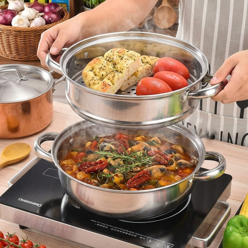Dampindsats med brød og tomater løftes over underdelen med en gryderet på en sort kogeplade