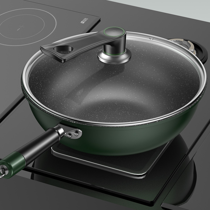Grøn wok med glaslåg på en sort kogeplade af glas, set skråt ovenfra