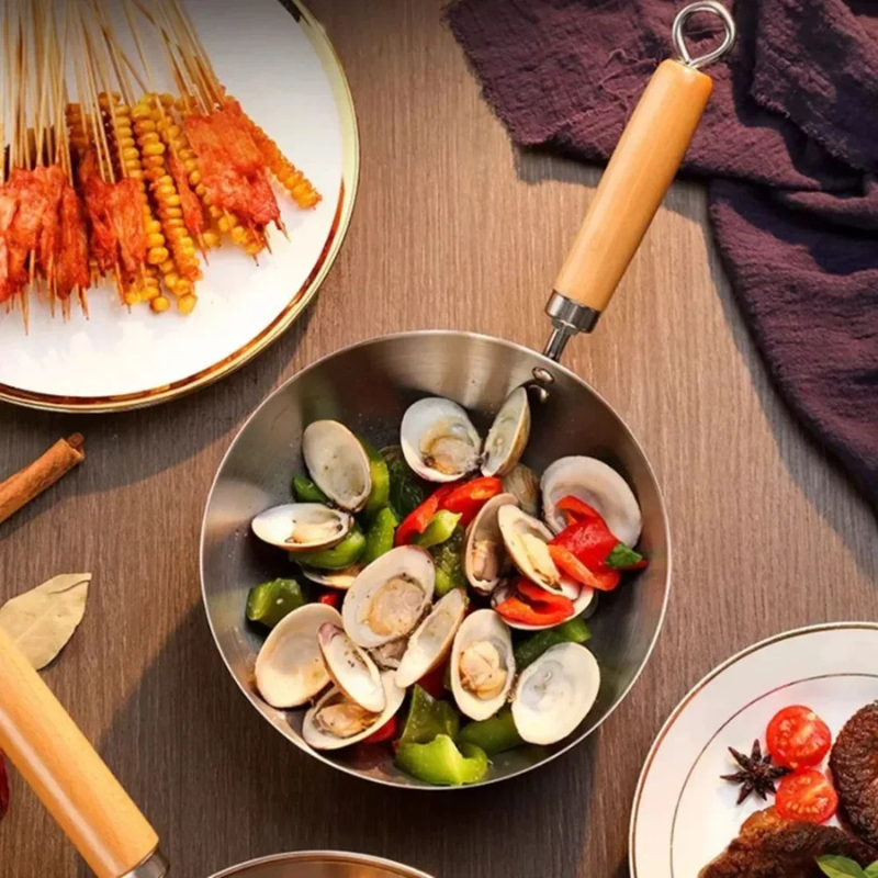 Wok med muslinger og grøn og rød peberfrugt, set ovenfra mellem tallerkener med grillspyd