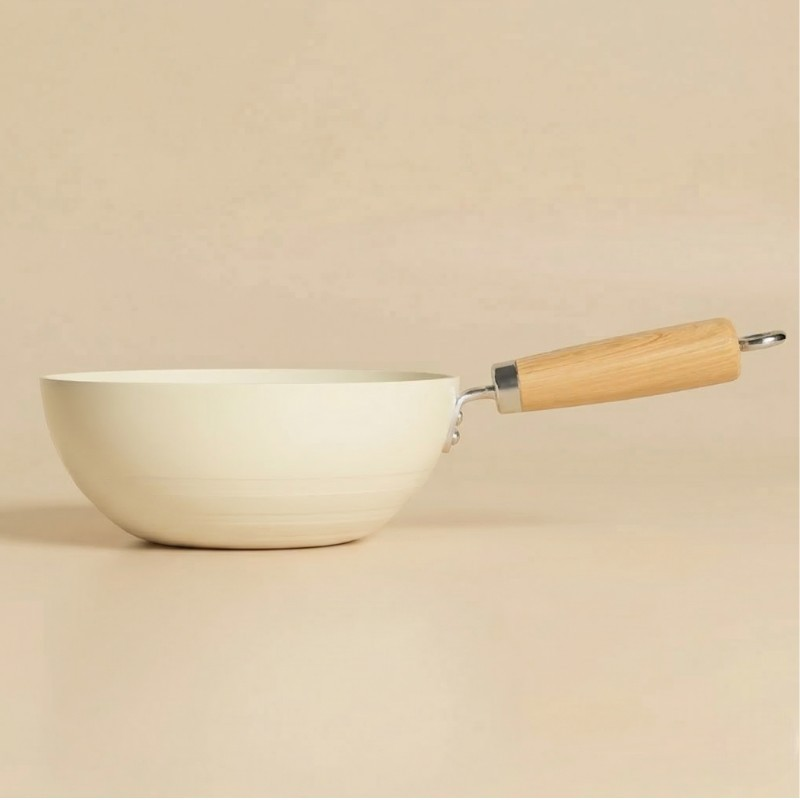 Le Tehana keramisk wok i cremefarve uden låg, set fra siden med lyst håndtag på beige baggrund