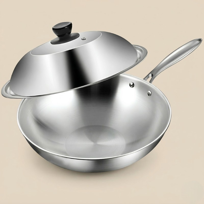 Le Ishizuchi wok i rustfrit stål med låget løftet over kanten og sort knop, på beige baggrund
