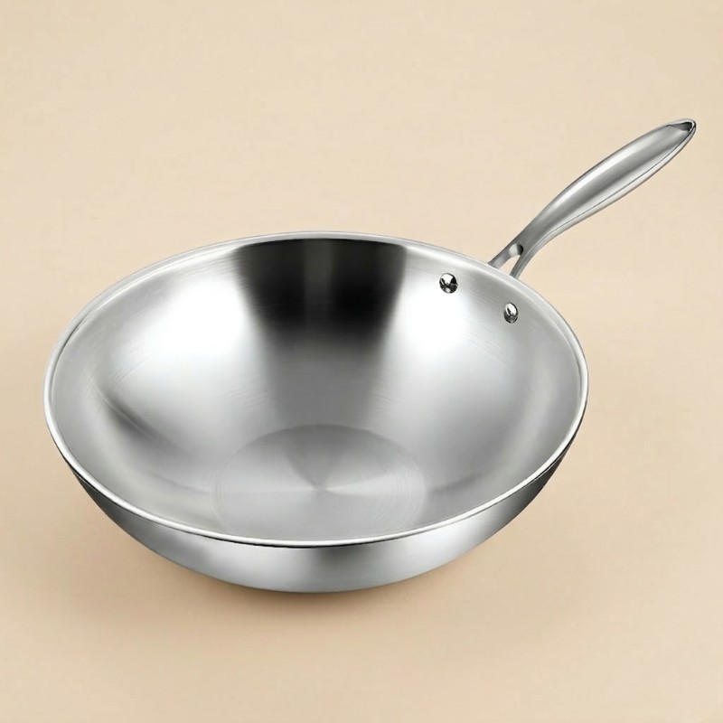 Wok i rustfrit stål uden låg, set skråt ovenfra med det lange skaft, på beige baggrund