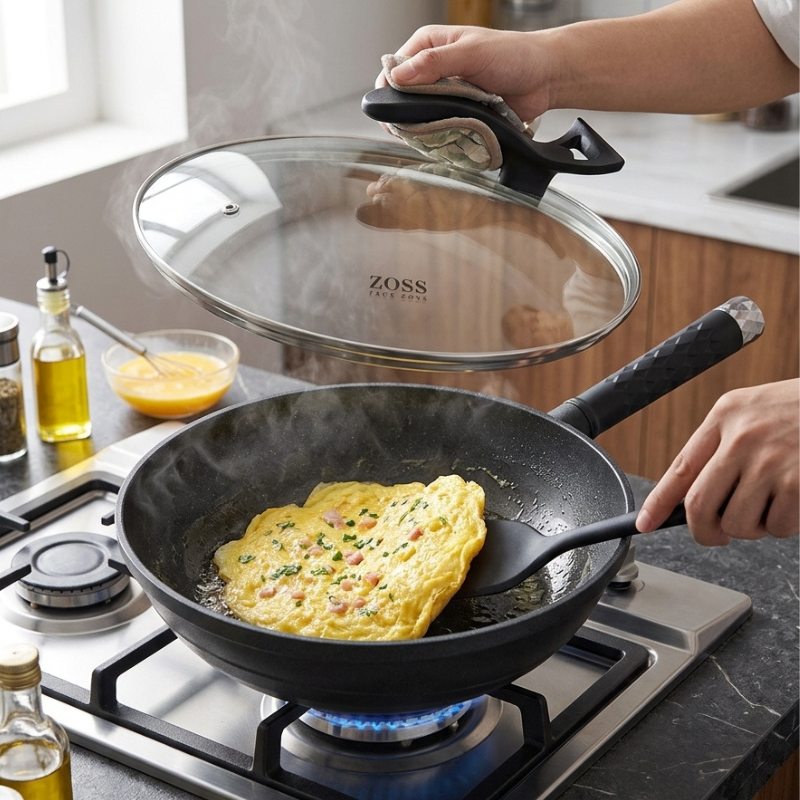 En hånd løfter glaslåget med en grydelap, mens en omelet steger i woken over et gasblus