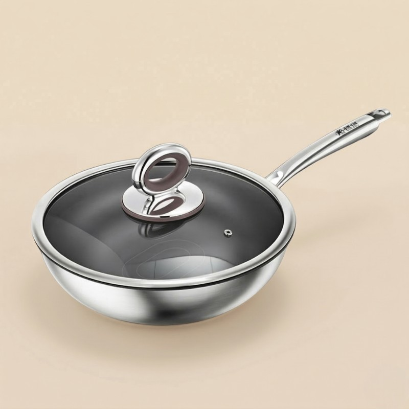 Le Tsumio wok i rustfrit stål med glaslåg og langt skaft, fotograferet på en lys beige baggrund