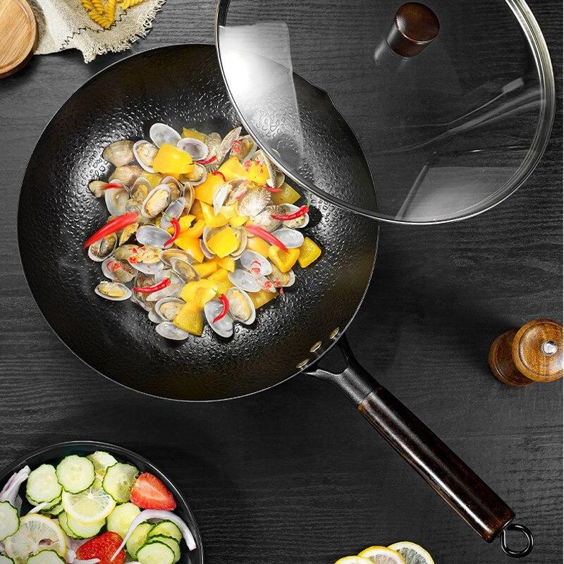 Woken set ovenfra med muslinger, gul peberfrugt og chili, glaslåget skubbet til side og en skål salat ved siden af