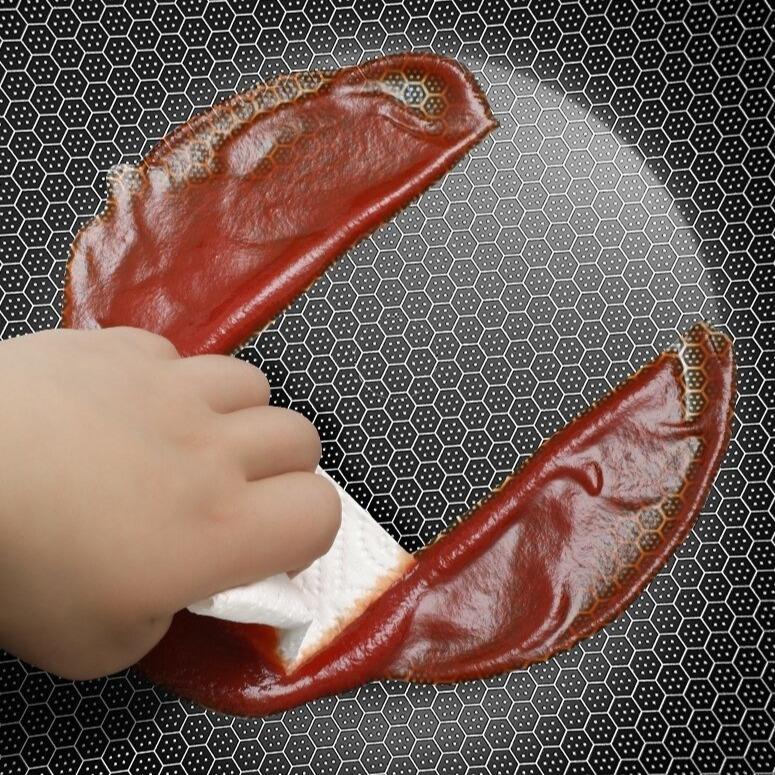 Hånd tørrer rød sauce af bikubeoverfladen med et stykke køkkenpapir