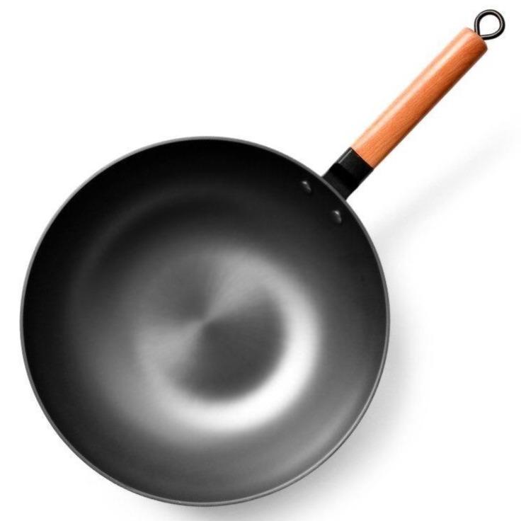 Wokken set lige oppefra på hvid baggrund med mørk stålflade og lyst træskaft