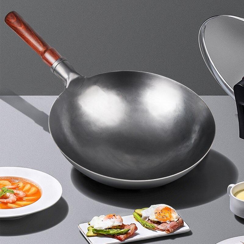 Wokpanden på et gråt bord ved siden af en tallerken suppe med rejer og et fad med pocherede æg på asparges