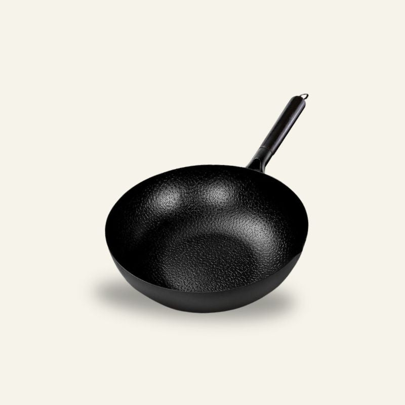 Le Norikura, sort wok med hamret overflade og langt mørkt skaft, set skråt ovenfra på en lys baggrund