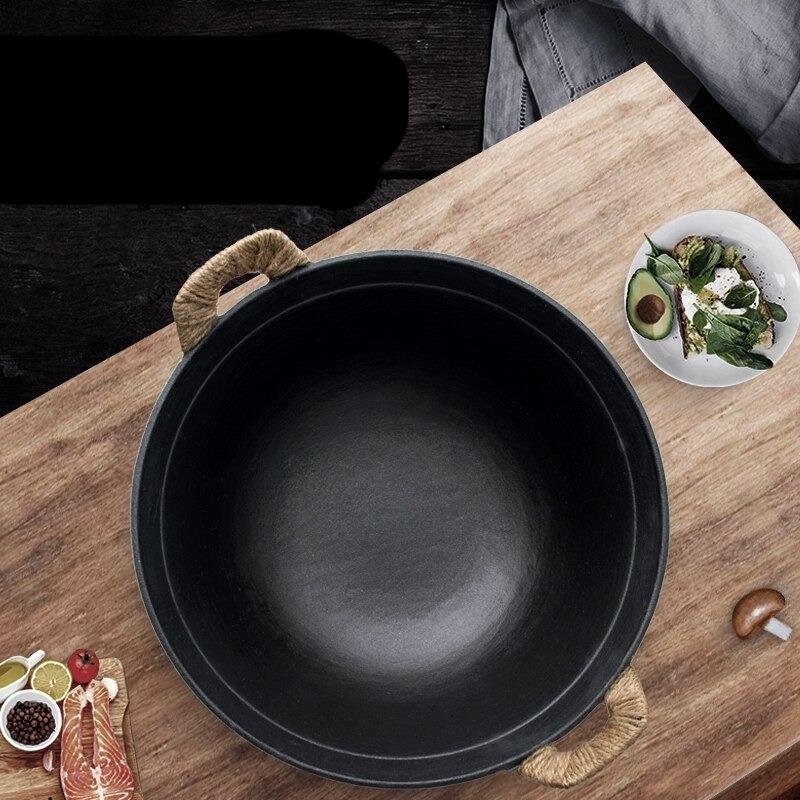 Wokpanden set ovenfra på et træbord med avocadomad på en tallerken og små skåle med krydderier ved siden af