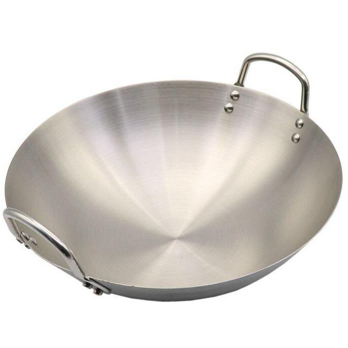 Le Tate wok i rustfrit stål set skråt fra siden på hvid baggrund, med to nittede hanke i metal