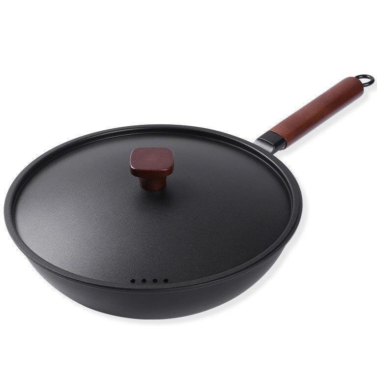 Le Tsukuba jern wok med låg og træknop, langt træhåndtag med ophængsring, på hvid baggrund