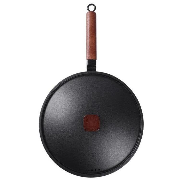 Jern wok set fra oven med låget på og træhåndtaget pegende opad, hvid baggrund