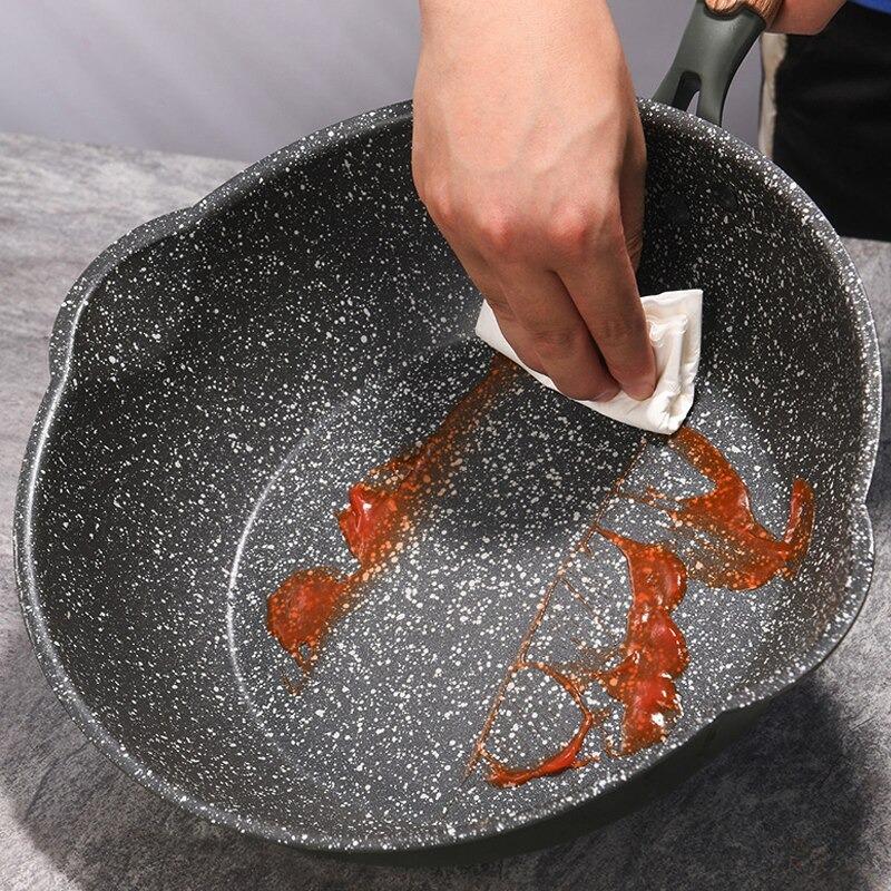 En hånd tørrer rød sauce af den prikkede belægning med et stykke køkkenrulle