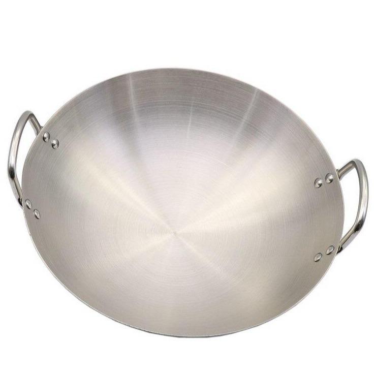 Le Yakushi wok i rustfrit stål set ovenfra på hvid baggrund, med to nittede hanke