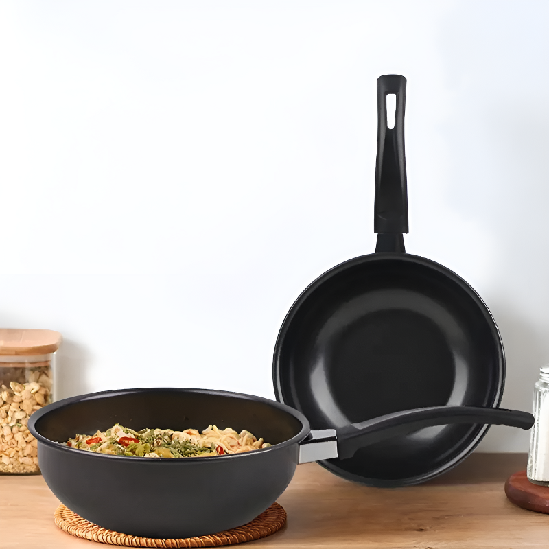 To små woks, den ene med nudler og grøntsager på en flettet bordskåner, den anden stillet på højkant bagved
