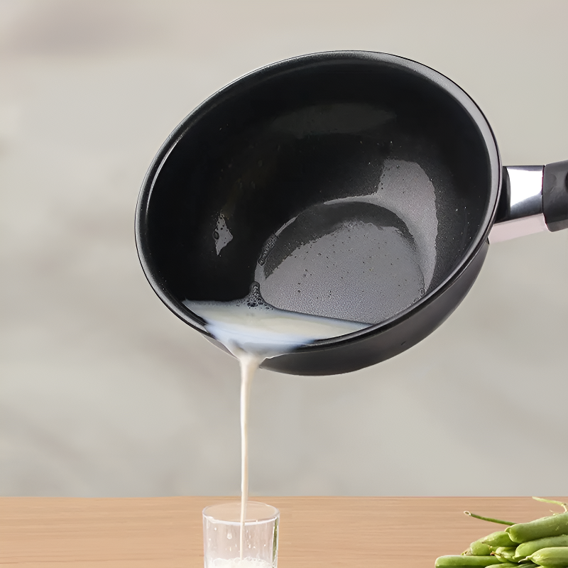 Hvid væske hældes ud gennem hældetuden i kanten af woken og ned i et glas