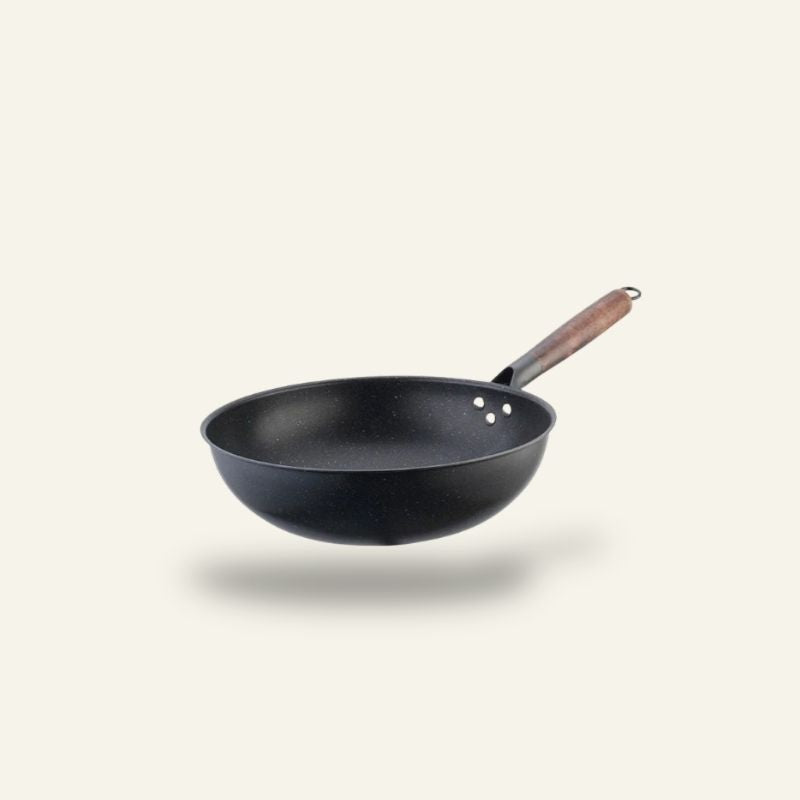 Le Kosanji wok keramisk i sort med træhåndtag, fotograferet fra siden på en lys baggrund