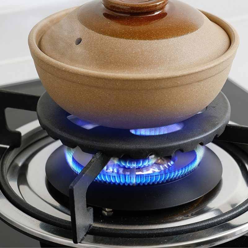 Rist til gasblus på et gaskomfur over en tændt blå gasflamme med en brun lergryde ovenpå
