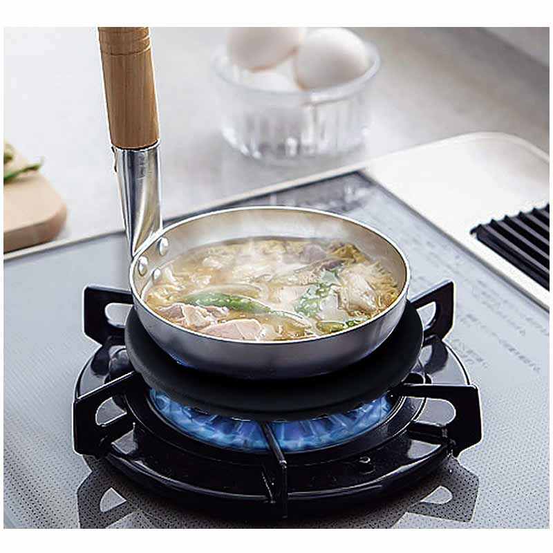 Lille gryde med træskaft og dampende suppe på en rist til gasblus over en blå gasflamme