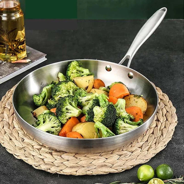 Stegepanden fyldt med broccoli, gulerødder og kartofler, stillet på en flettet bordskåner