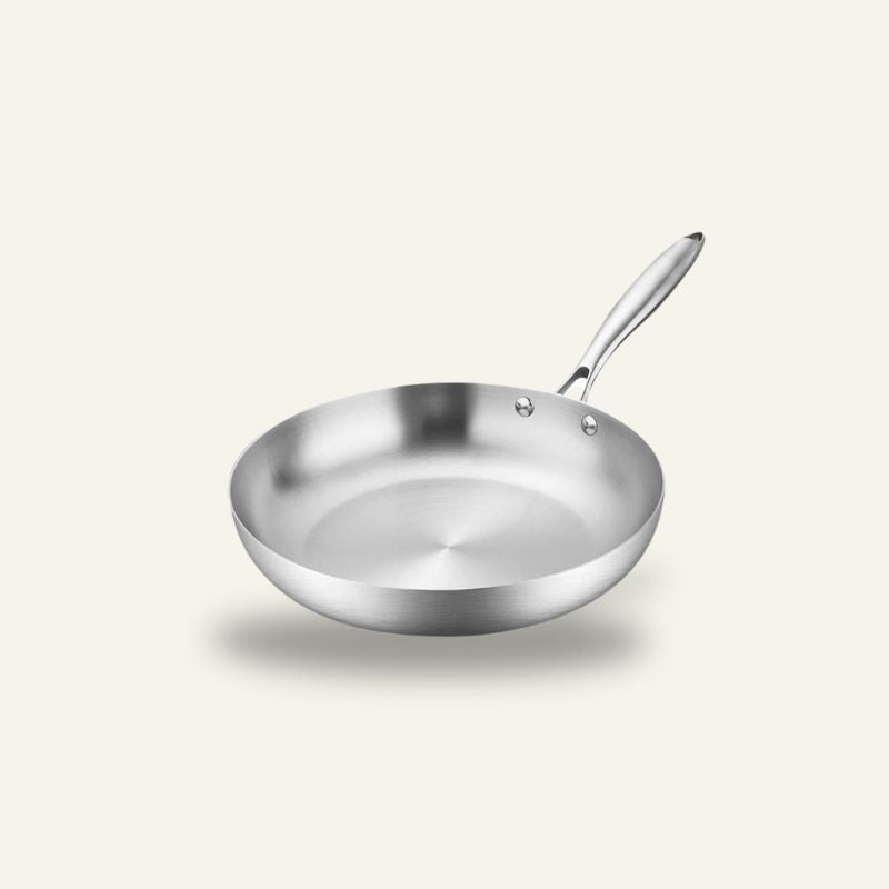 Le Shari stegepande i rustfrit stål med langt greb, set skråt ovenfra på en lys baggrund