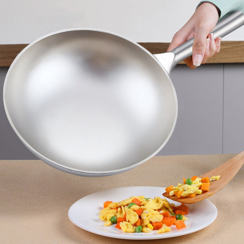 Hånd holder den tomme wok over en tallerken med røræg, ærter og gulerod, der øses op med en træspatel